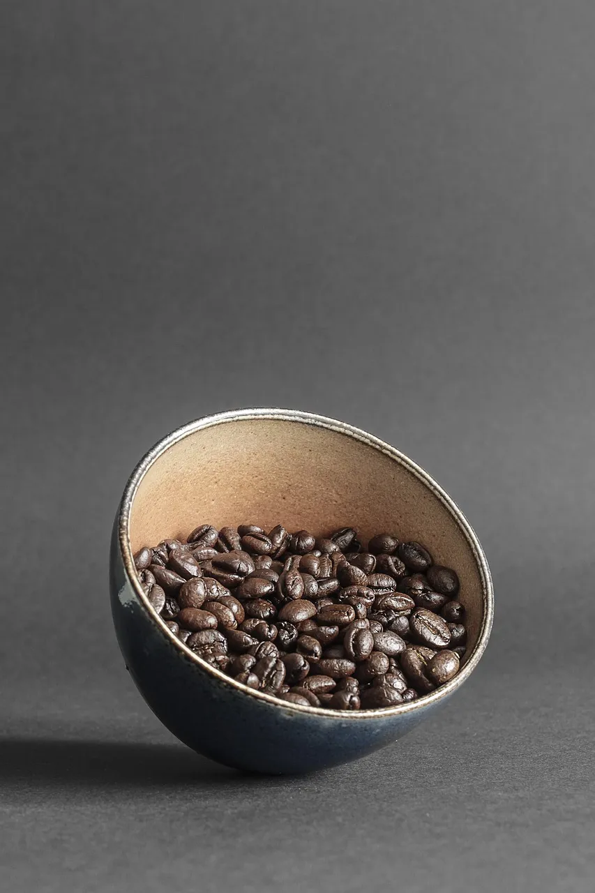 Bowl filled with roasted coffee beans, showcasing their rich texture and dark brown color.